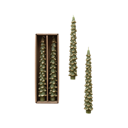 Three pine tree-shaped candles in olive green with gold glitter accents, shown with two candles in a brown gift box and one candle standing outside on a white background.