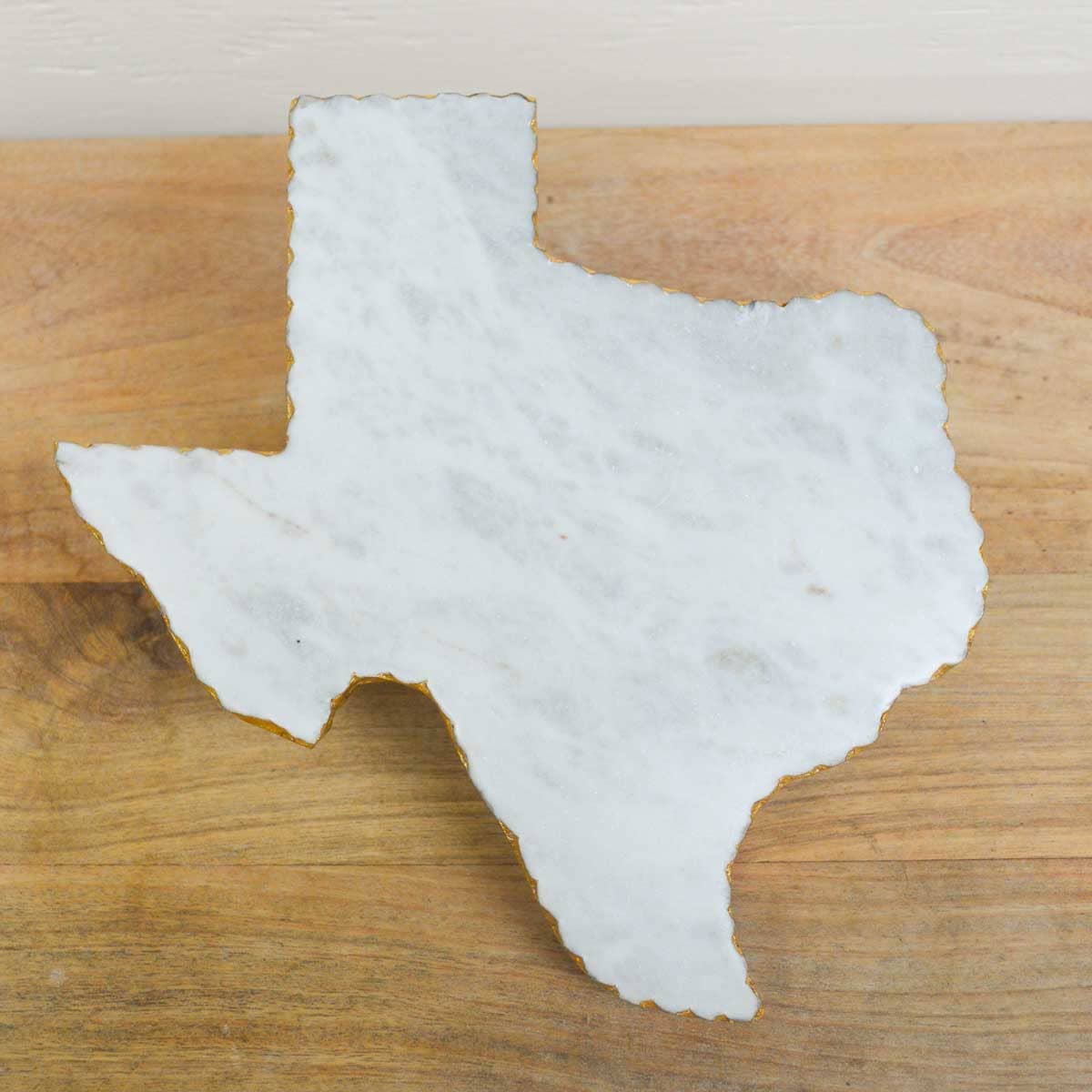 Marble cutting board shaped like the state of Texas on a wooden surface