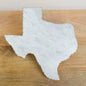 Marble cutting board shaped like the state of Texas on a wooden surface
