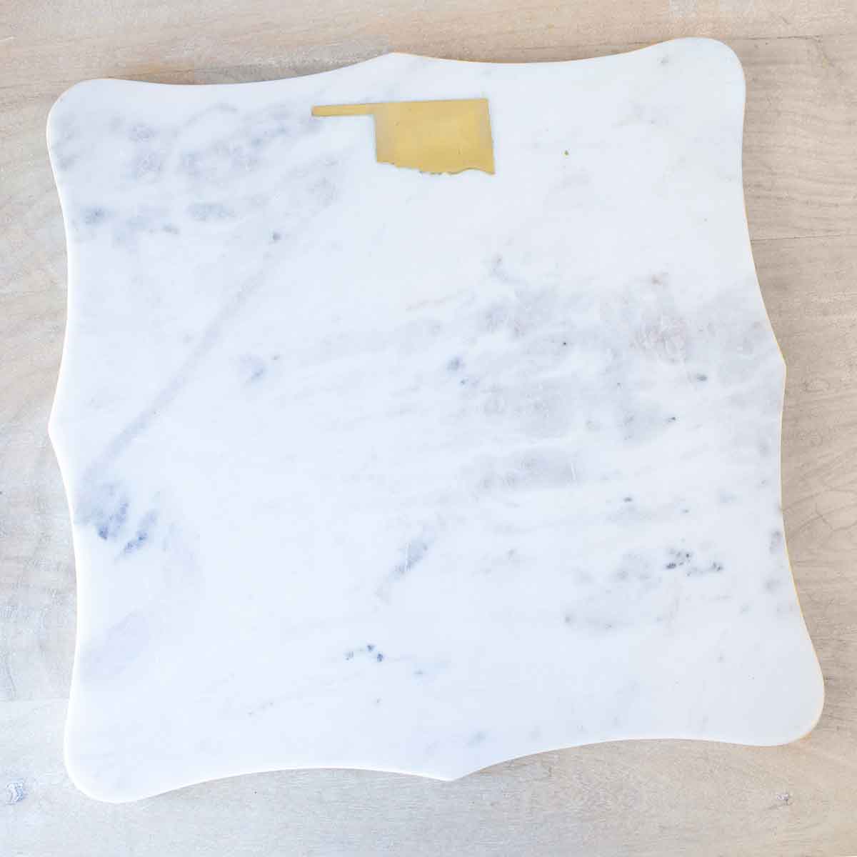 Marble-patterned serving board with a gold state of Oklahoma