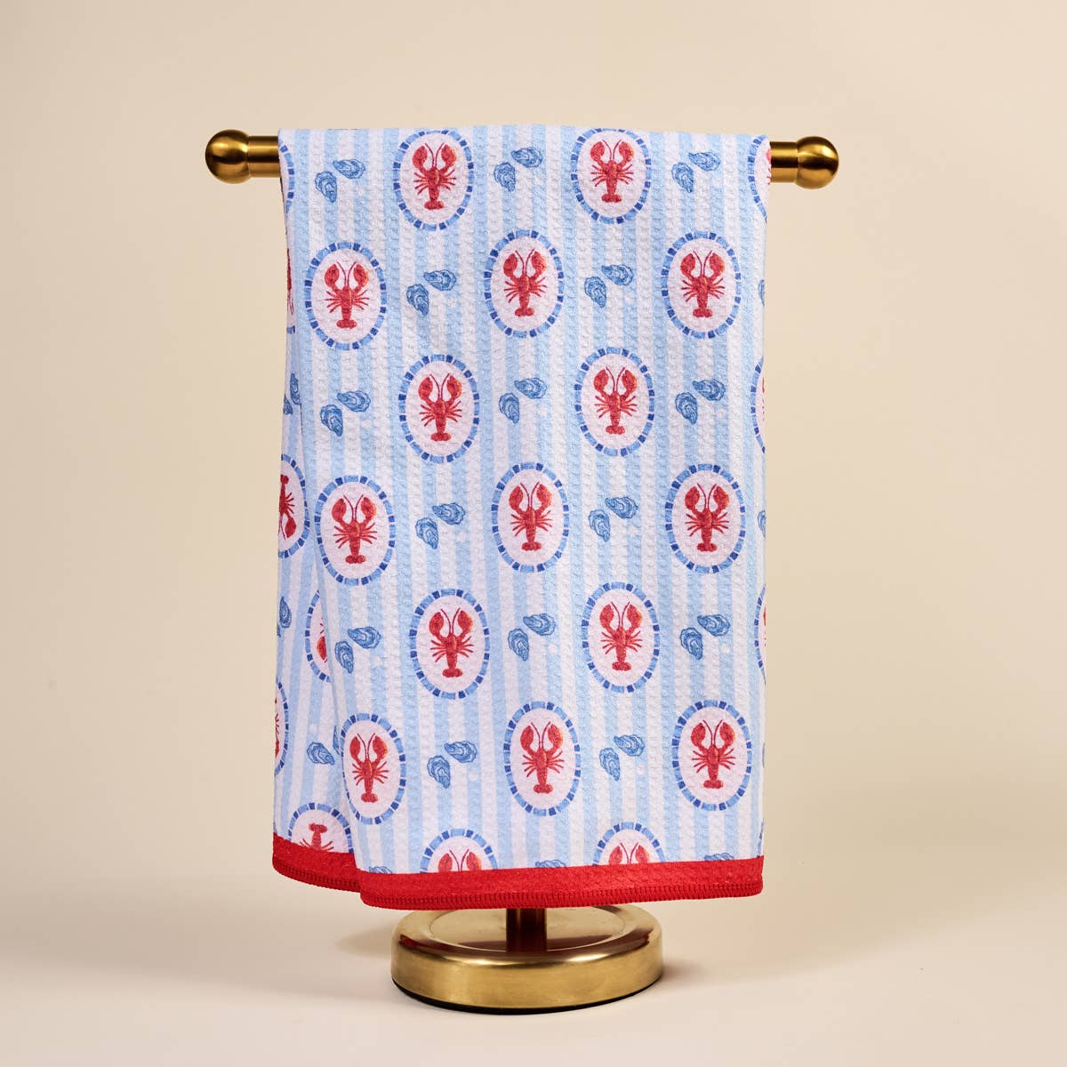 Kitchen tea Towel with lobster pattern hanging on a gold towel rack