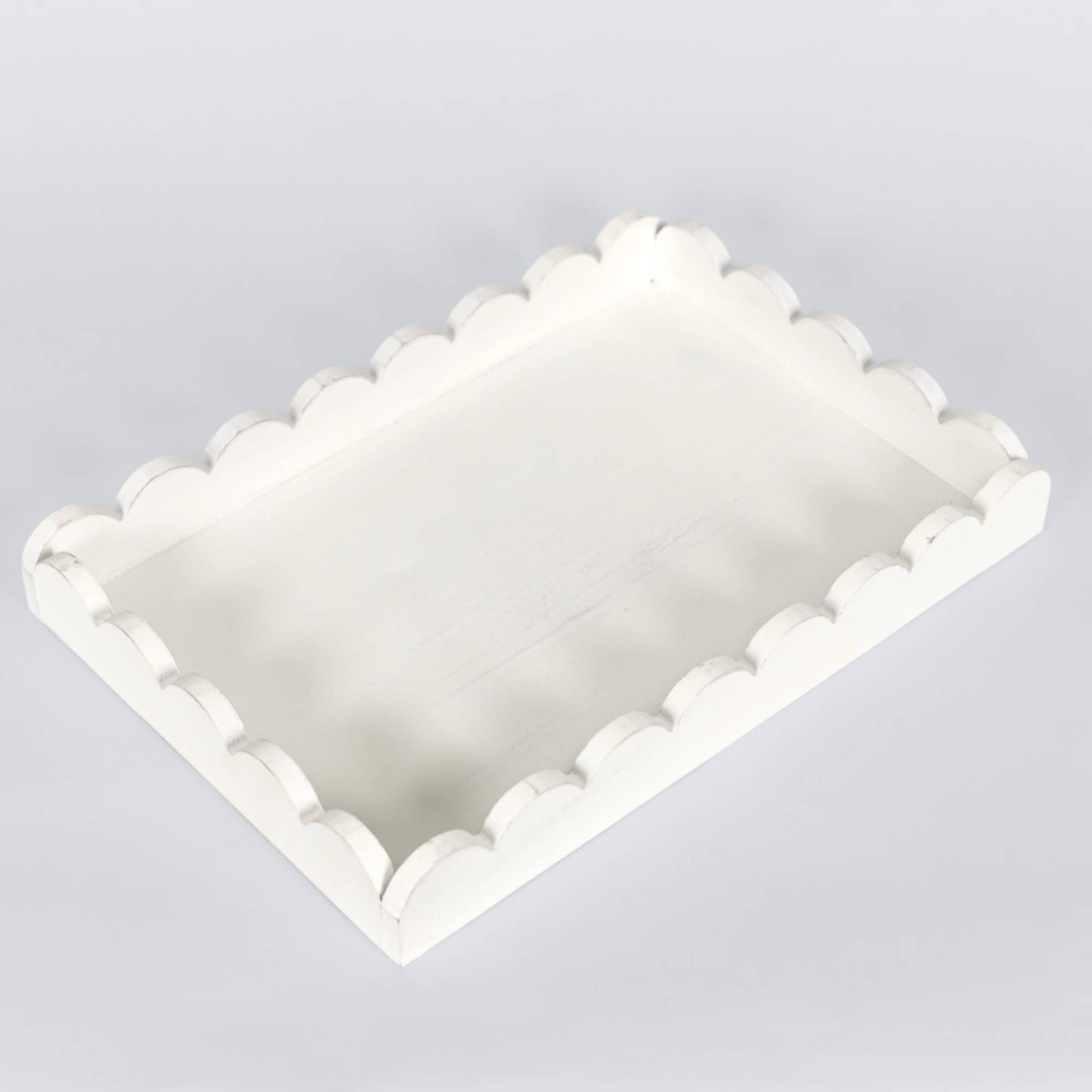 White decorative tray with scalloped edge on a light gray background