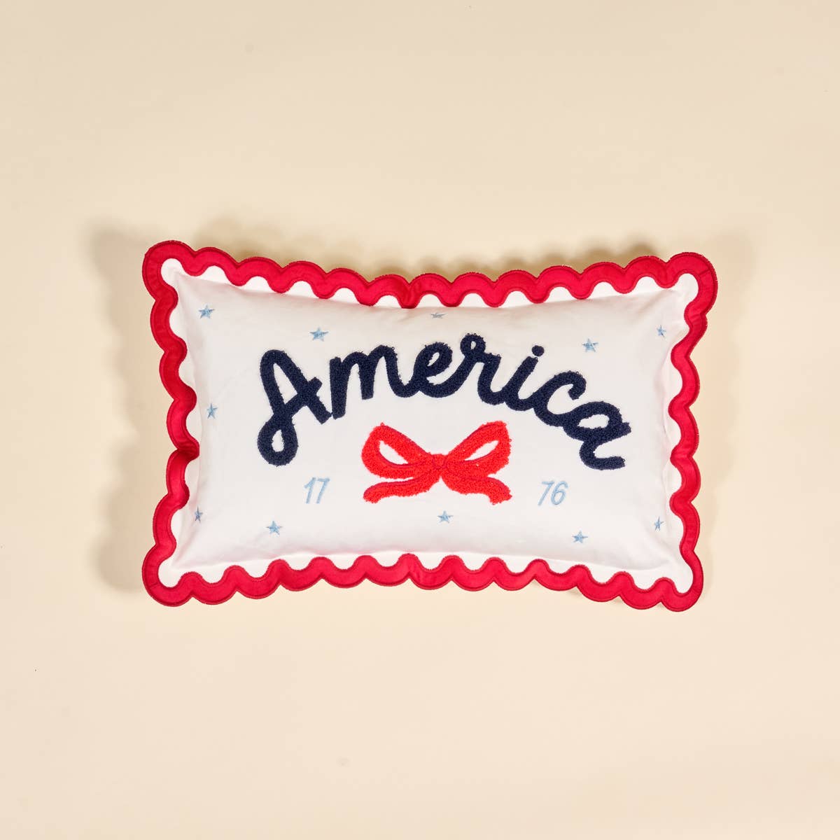 Decorative pillow with 'America' and a bow design with scalloped edges