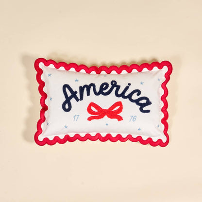 Decorative pillow with 'America' and a bow design with scalloped edges