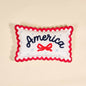 Decorative pillow with 'America' and a bow design with scalloped edges