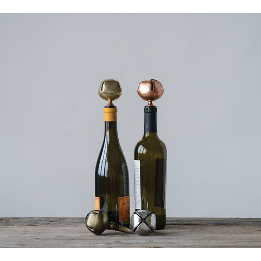 Two wine bottles with decorative bottle stoppers on a wooden surface against a light gray background